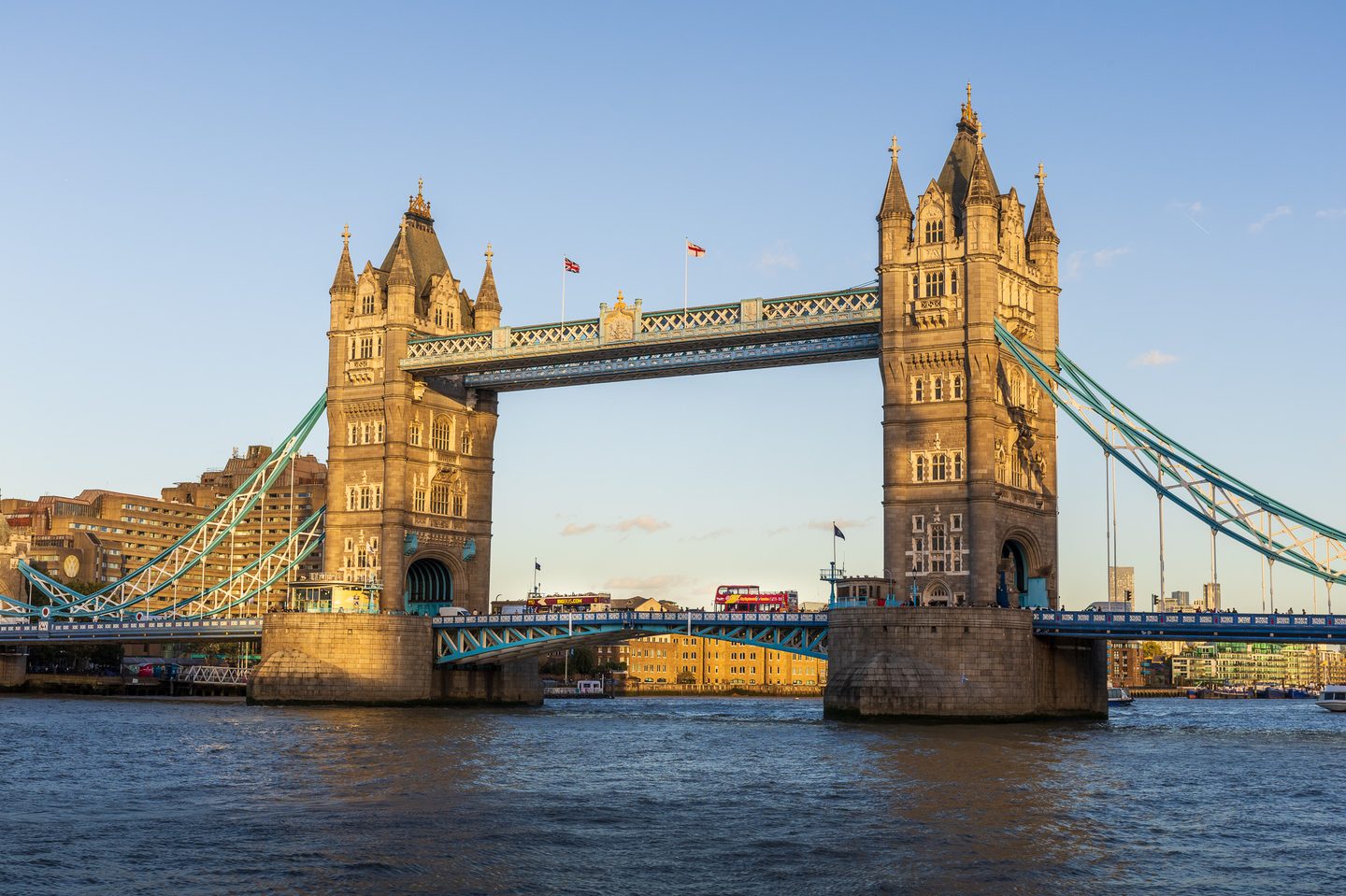 Tower Bridge in warm evening light, with a red double-decker bus crossing